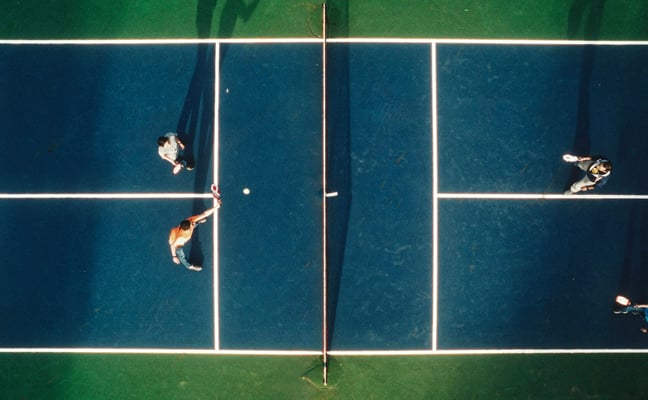 Aerial view of four people playing pickleball on a blue court