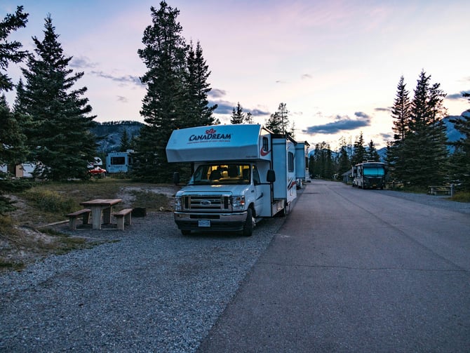Motorhome parked in a pull-through campground row at twilight