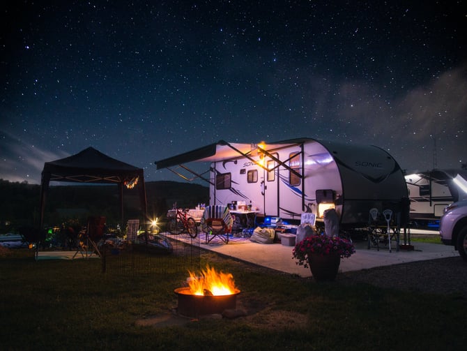 RV trailer set up at a back-in campsite under a starry sky